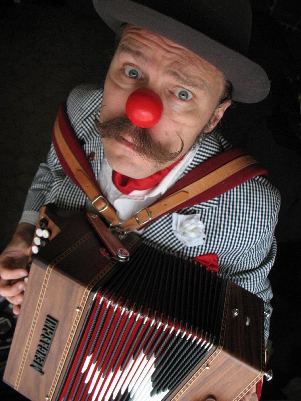 Guy Heathcote in his red nose playing the accordion 