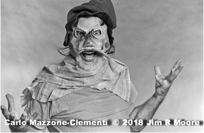 Carlo Mazzone-Clementi wearing Brighella mask made by Stanley Allan Sherman. with his hands open and up at his side